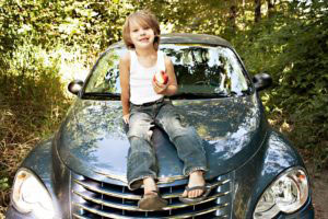 Boy eating an apple while sitting on my car. Sometimes my tolerance spreads wide.