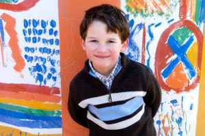 Boy standing a colorful graffiti wall and smiling gently